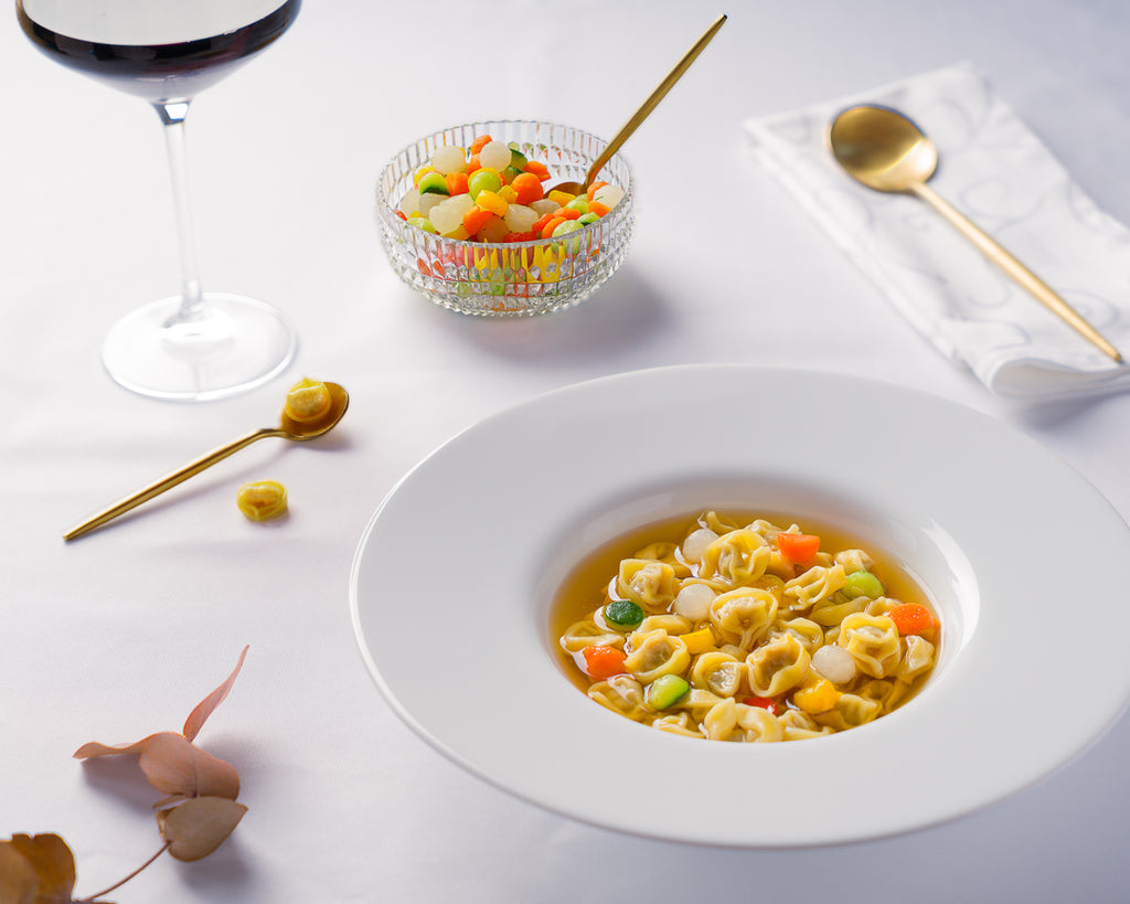 Tortellino “Raviolino d’oro” con bottoni di verdure croccanti in brodo al profumo di liquirizia.